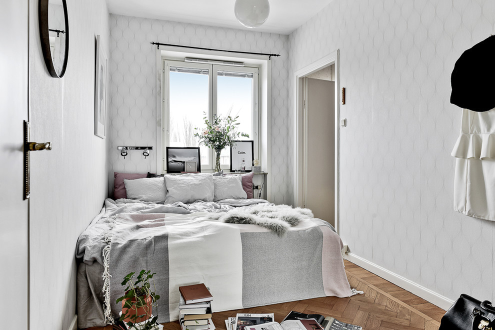 Modelo de dormitorio principal escandinavo de tamaño medio con paredes blancas y suelo de madera en tonos medios