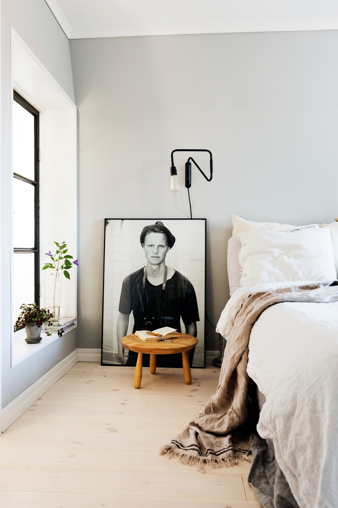 Nordisk inredning av ett mellanstort sovrum, med grå väggar och ljust trägolv