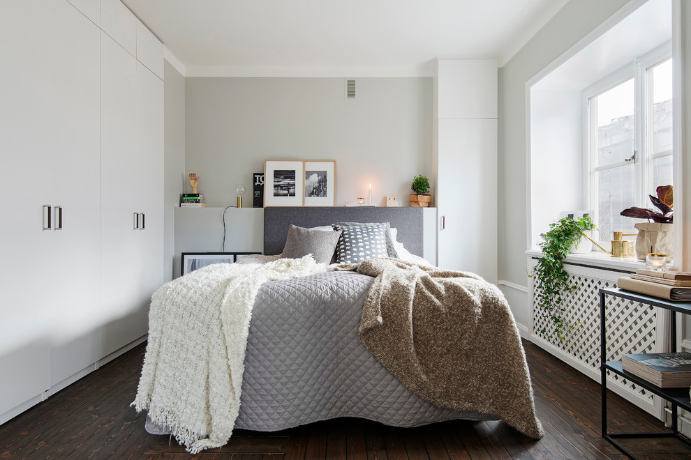 Foto på ett mellanstort minimalistiskt sovrum, med grå väggar och mörkt trägolv