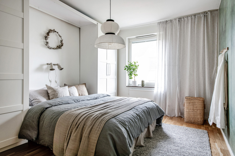 Idéer för ett minimalistiskt sovrum, med vita väggar, mellanmörkt trägolv och brunt golv