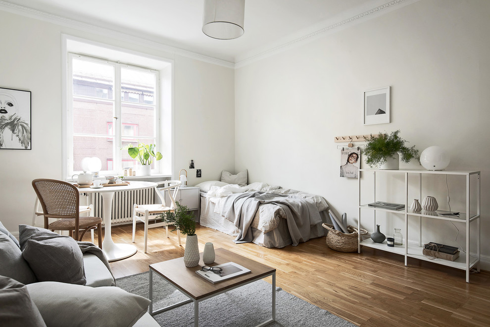 Idéer för ett skandinaviskt sovrum, med vita väggar, mellanmörkt trägolv och brunt golv