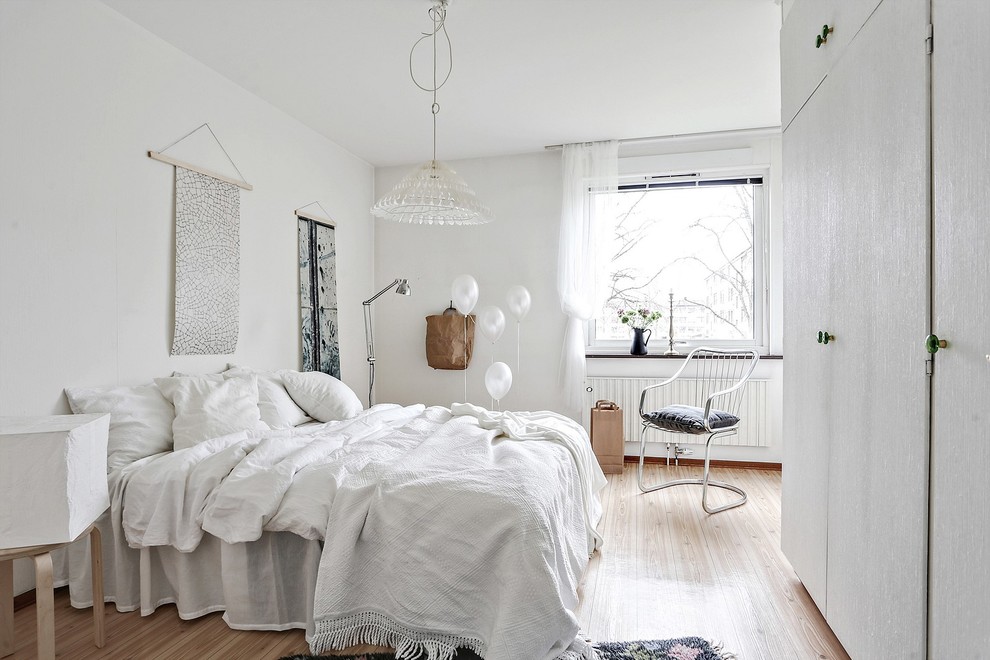 Idéer för ett skandinaviskt sovrum, med vita väggar, mellanmörkt trägolv och beiget golv