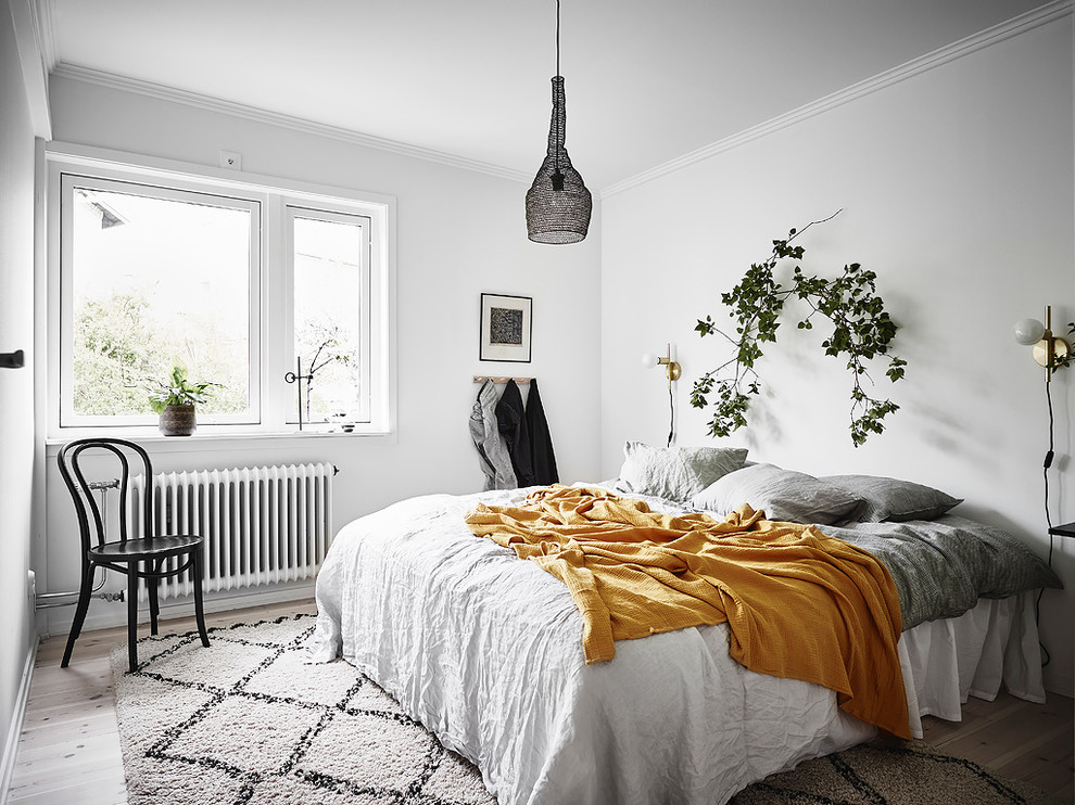 Modelo de dormitorio nórdico con paredes blancas, suelo de madera clara y suelo beige