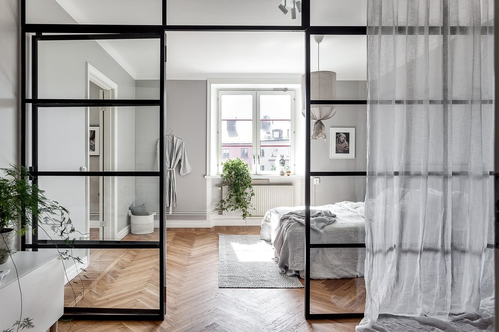 Cette photo montre une grande chambre parentale scandinave avec un mur gris, parquet clair et verrière.