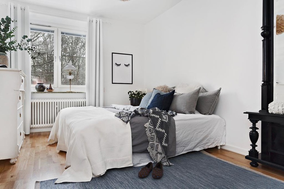 Foto di una camera matrimoniale nordica di medie dimensioni con pareti bianche, pavimento in legno massello medio e pavimento beige