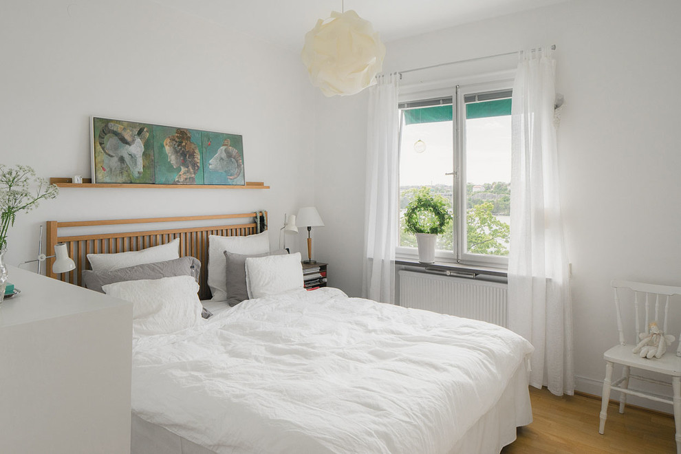 Medium sized scandi master bedroom in Stockholm with white walls, light hardwood flooring and no fireplace.