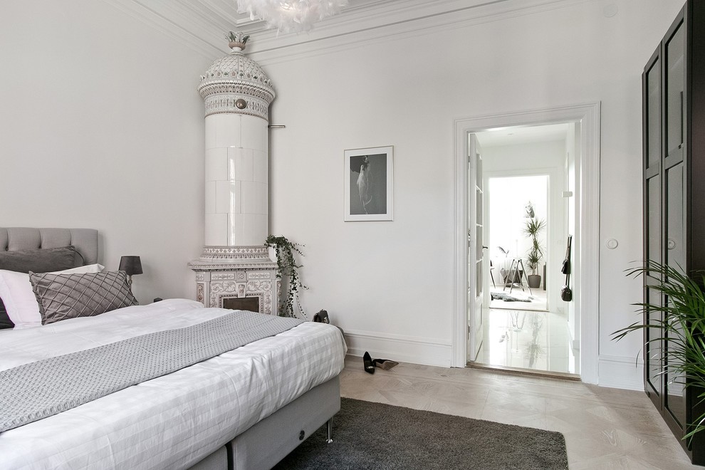 Mittelgroßes Skandinavisches Hauptschlafzimmer mit hellem Holzboden, beigem Boden, weißer Wandfarbe, Kaminofen und Kaminumrandung aus Metall in Sonstige