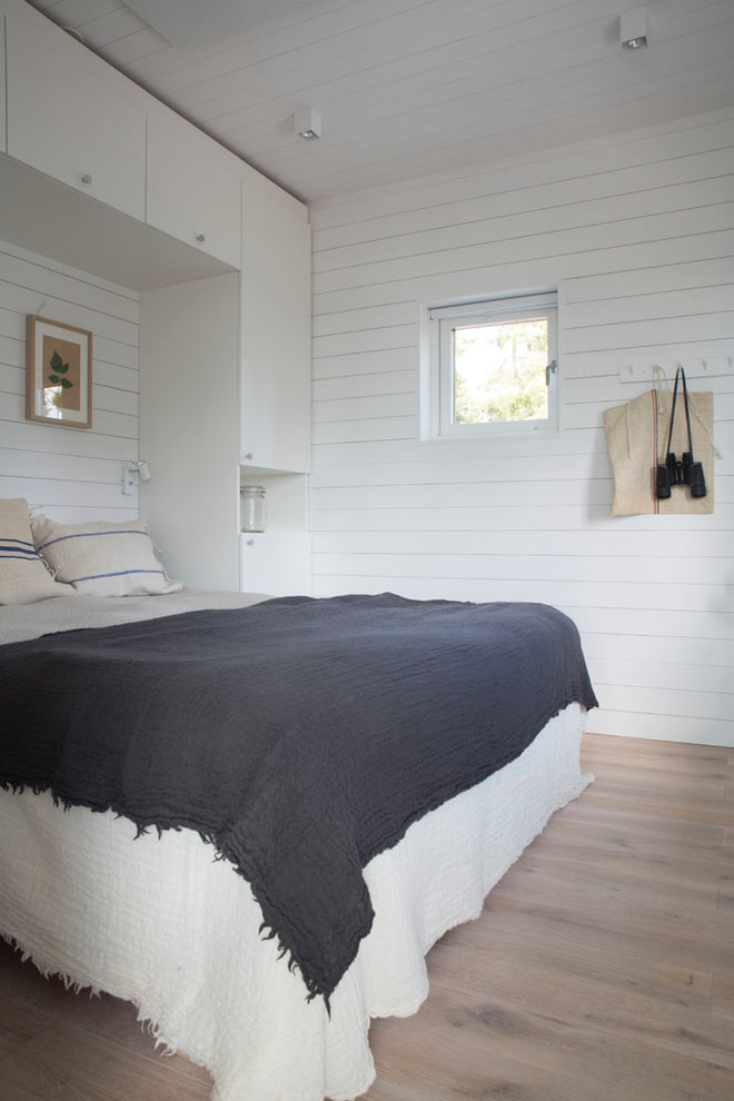 Imagen de dormitorio principal marinero sin chimenea con paredes blancas y suelo de madera clara