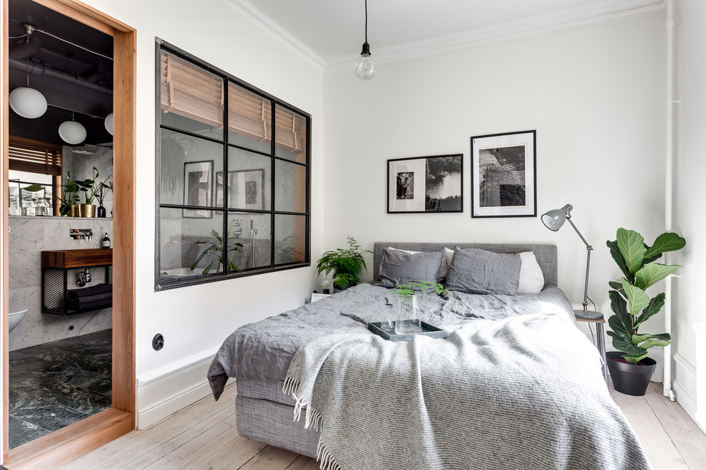 Imagen de dormitorio principal y gris y blanco escandinavo de tamaño medio sin chimenea con paredes blancas y suelo de madera clara