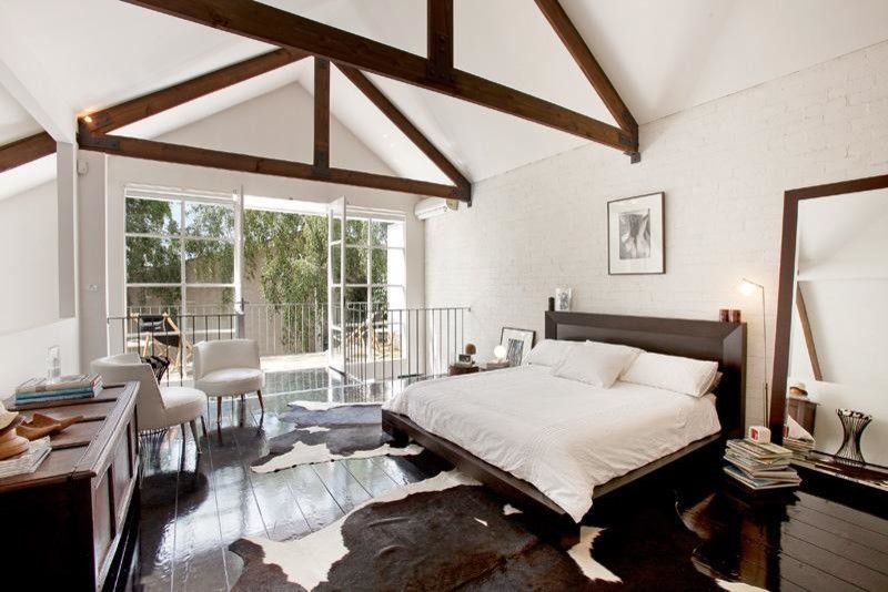 Foto de dormitorio tipo loft urbano grande sin chimenea con paredes blancas, suelo de madera oscura y marco de chimenea de metal