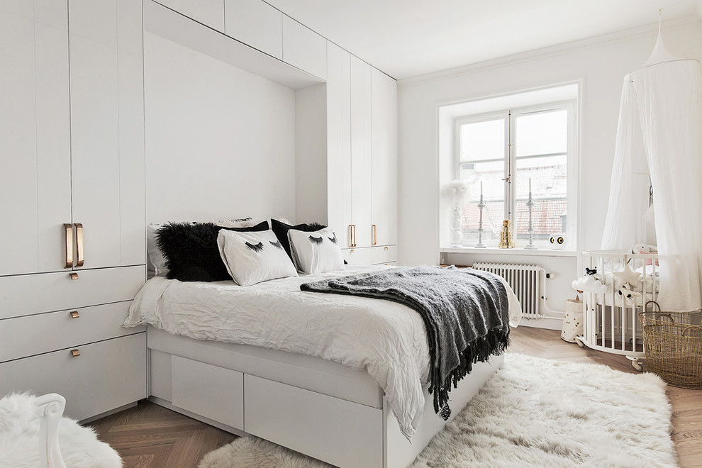 Mittelgroßes Nordisches Hauptschlafzimmer ohne Kamin mit weißer Wandfarbe und hellem Holzboden in Stockholm