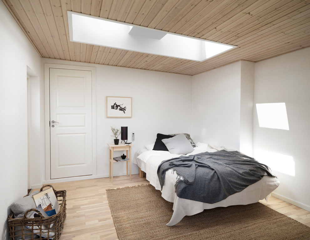 На фото: хозяйская спальня среднего размера на мансарде в скандинавском стиле с белыми стенами и светлым паркетным полом