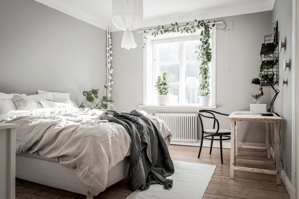 На фото: хозяйская спальня среднего размера в скандинавском стиле с серыми стенами, паркетным полом среднего тона и коричневым полом без камина