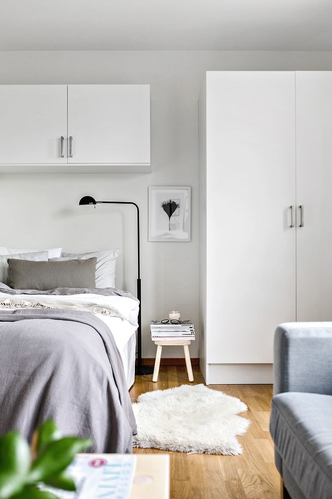 Nordisches Hauptschlafzimmer mit weißer Wandfarbe, braunem Holzboden und orangem Boden in Stockholm