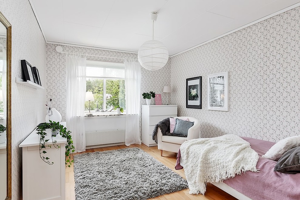 Cette image montre une chambre d'amis grise et rose nordique de taille moyenne avec un mur gris et un sol en bois brun.