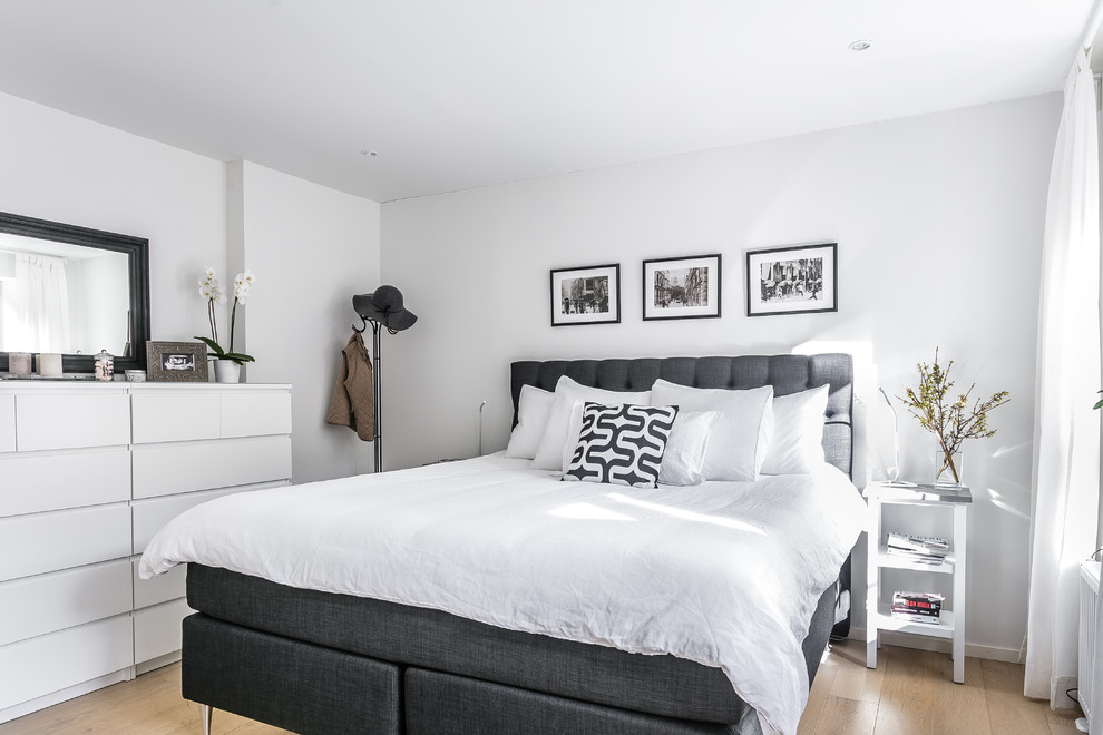 Mid-sized danish master light wood floor and beige floor bedroom photo in Malmo with white walls