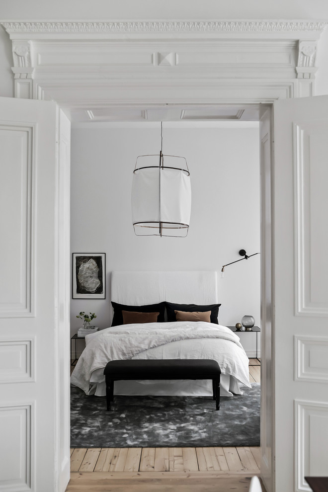 Nordisches Hauptschlafzimmer mit weißer Wandfarbe und hellem Holzboden in Göteborg