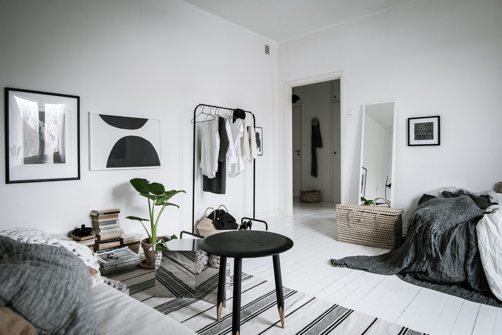 Scandinavian bedroom in Gothenburg with white walls, painted wood flooring and white floors.
