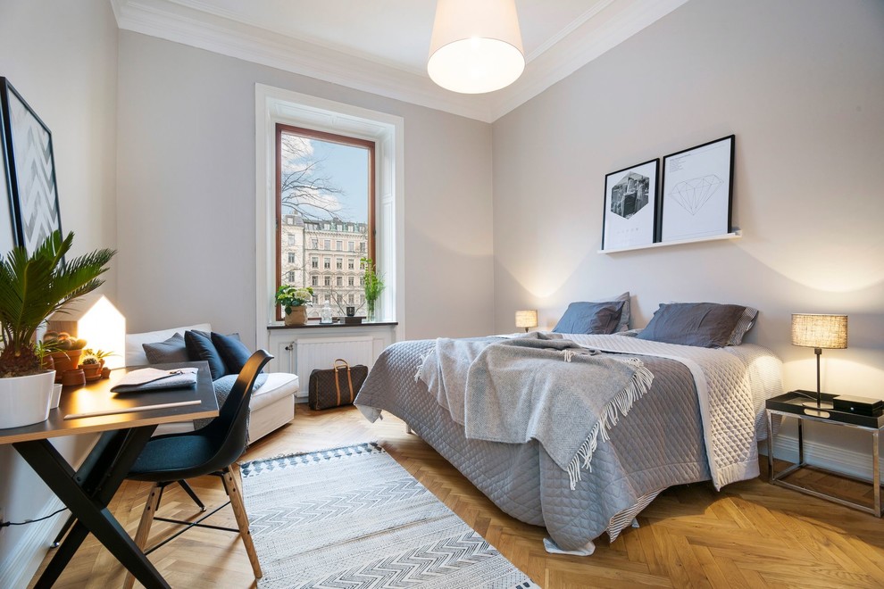 Mittelgroßes Skandinavisches Hauptschlafzimmer ohne Kamin mit grauer Wandfarbe und braunem Holzboden in Stockholm