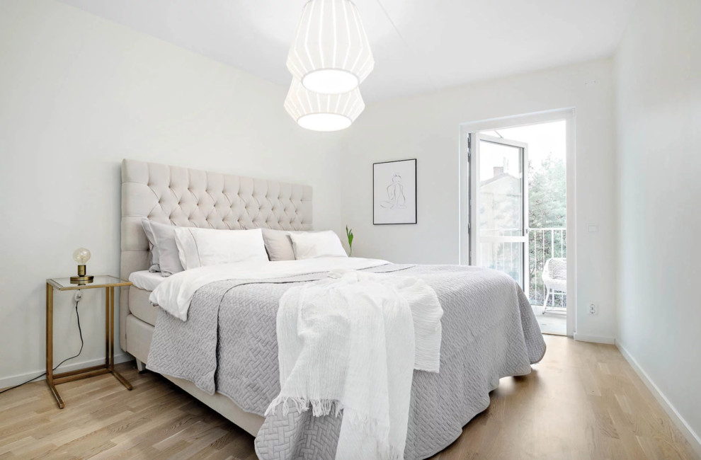Modelo de dormitorio principal tradicional renovado de tamaño medio con paredes blancas, suelo de madera clara y suelo beige