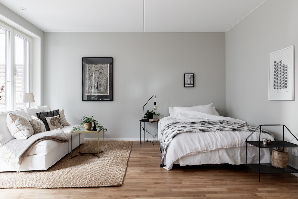 Mid-sized danish medium tone wood floor and brown floor bedroom photo in Stockholm with gray walls
