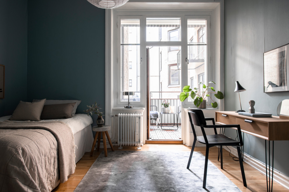 Foto di una camera da letto scandinava con pareti blu, pavimento in legno massello medio e pavimento marrone