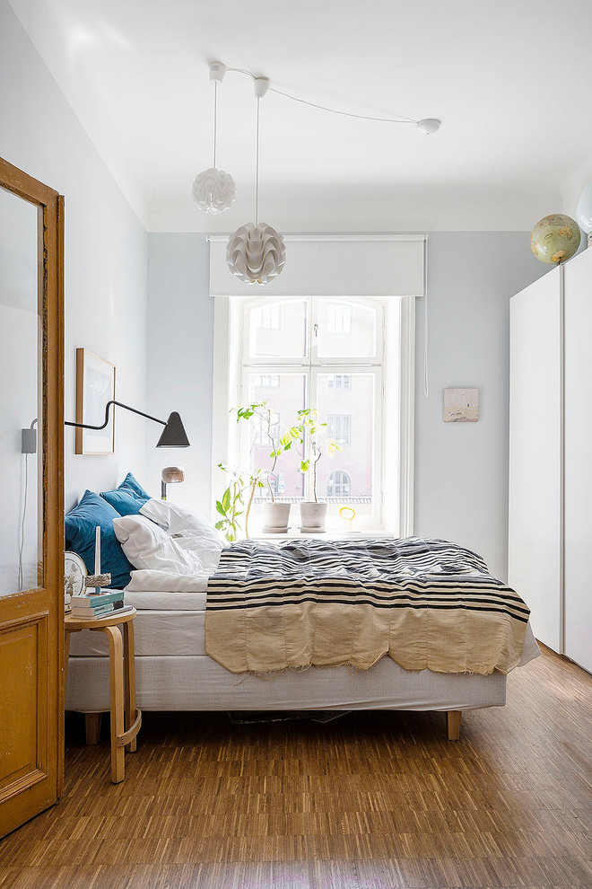 Aménagement d'une chambre parentale scandinave de taille moyenne avec un mur gris, un sol en bois brun et aucune cheminée.