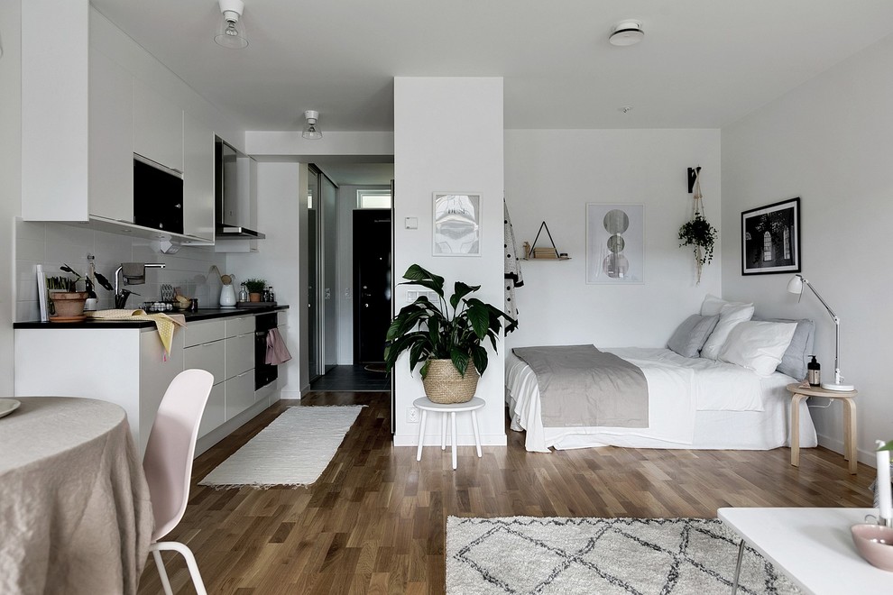 Small scandi grey and brown bedroom with white walls, medium hardwood flooring and brown floors.