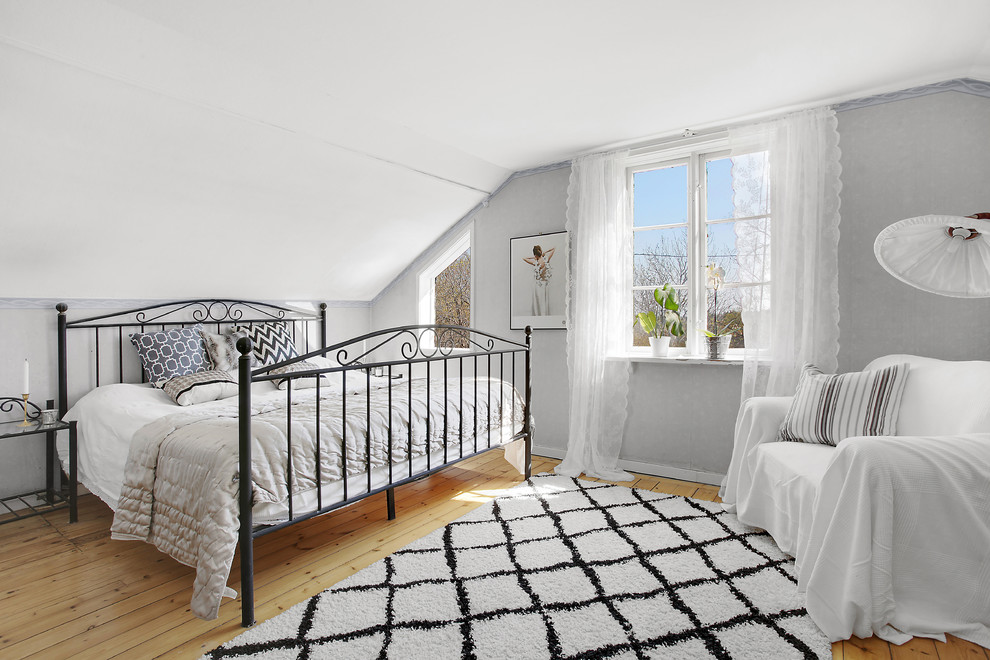 This is an example of a medium sized scandi master bedroom in Stockholm with grey walls and light hardwood flooring.