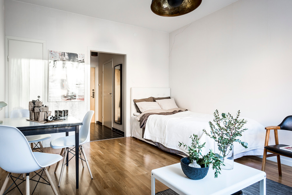 Bild på ett mellanstort minimalistiskt sovrum, med vita väggar och mellanmörkt trägolv