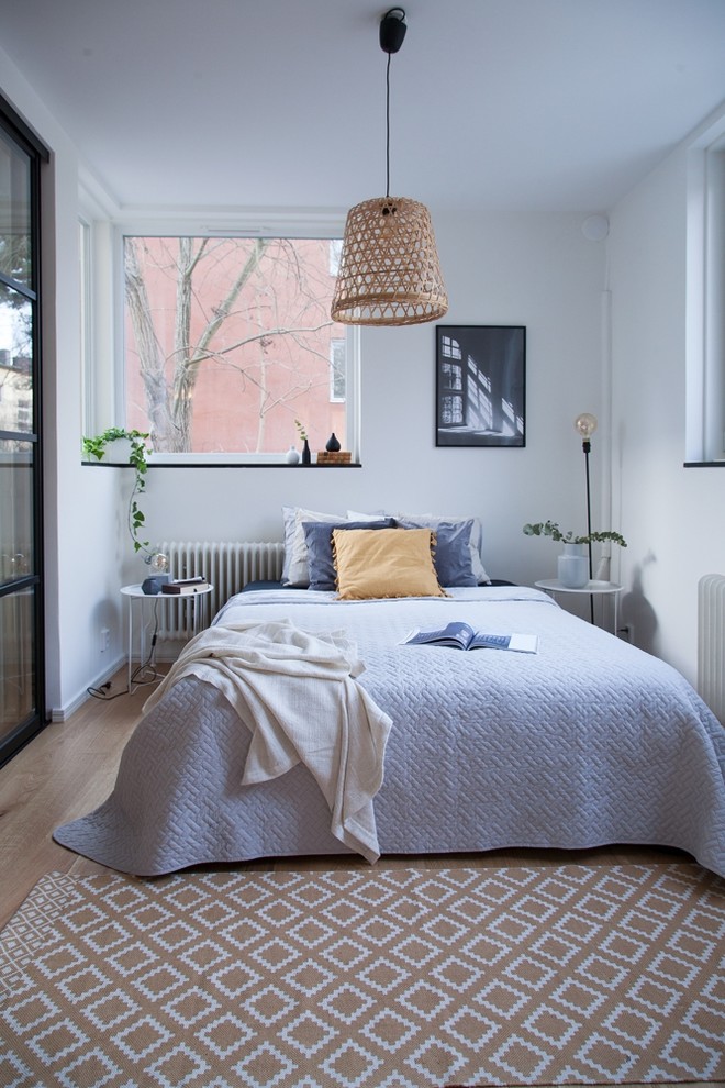 Mittelgroßes Skandinavisches Hauptschlafzimmer mit weißer Wandfarbe, hellem Holzboden und beigem Boden in Stockholm