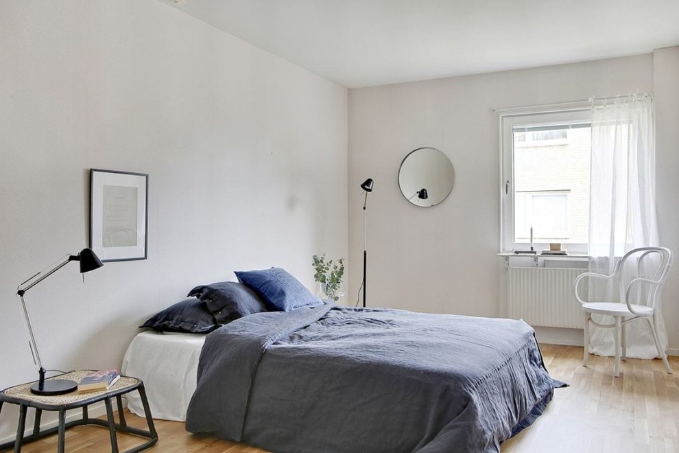 Small scandinavian bedroom in Malmo with white walls, light hardwood flooring and beige floors.