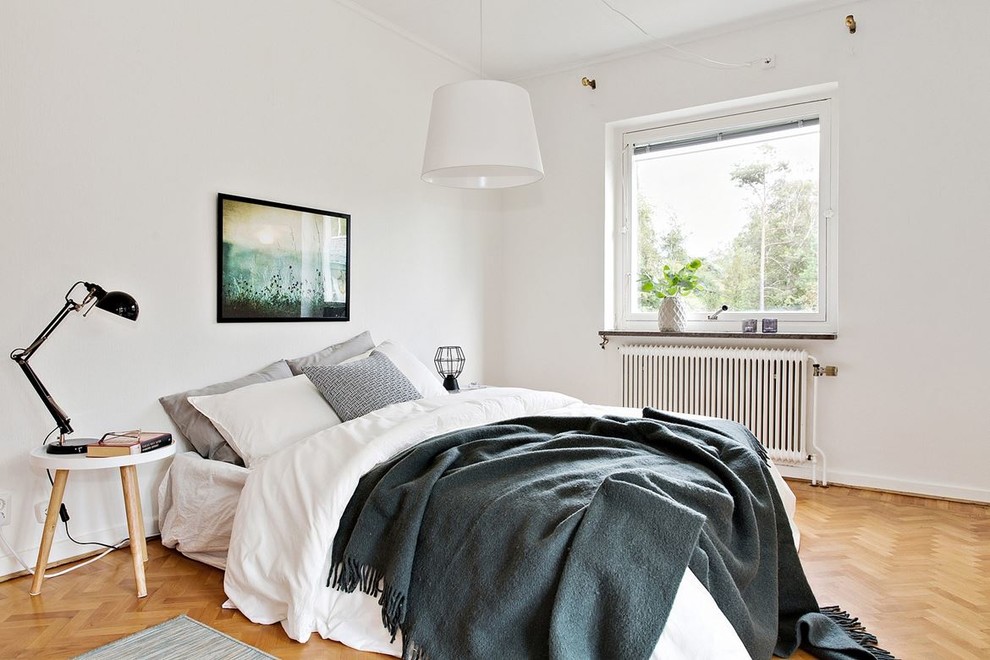 Foto på ett skandinaviskt sovrum, med vita väggar, mellanmörkt trägolv och brunt golv