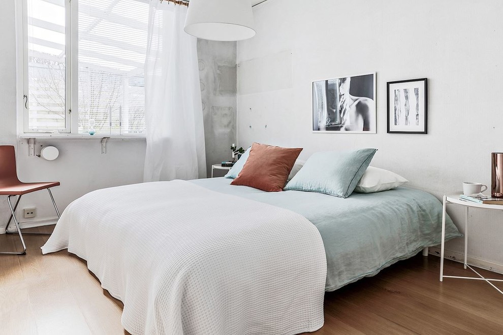 Nordisches Hauptschlafzimmer mit weißer Wandfarbe, braunem Boden und hellem Holzboden in Malmö
