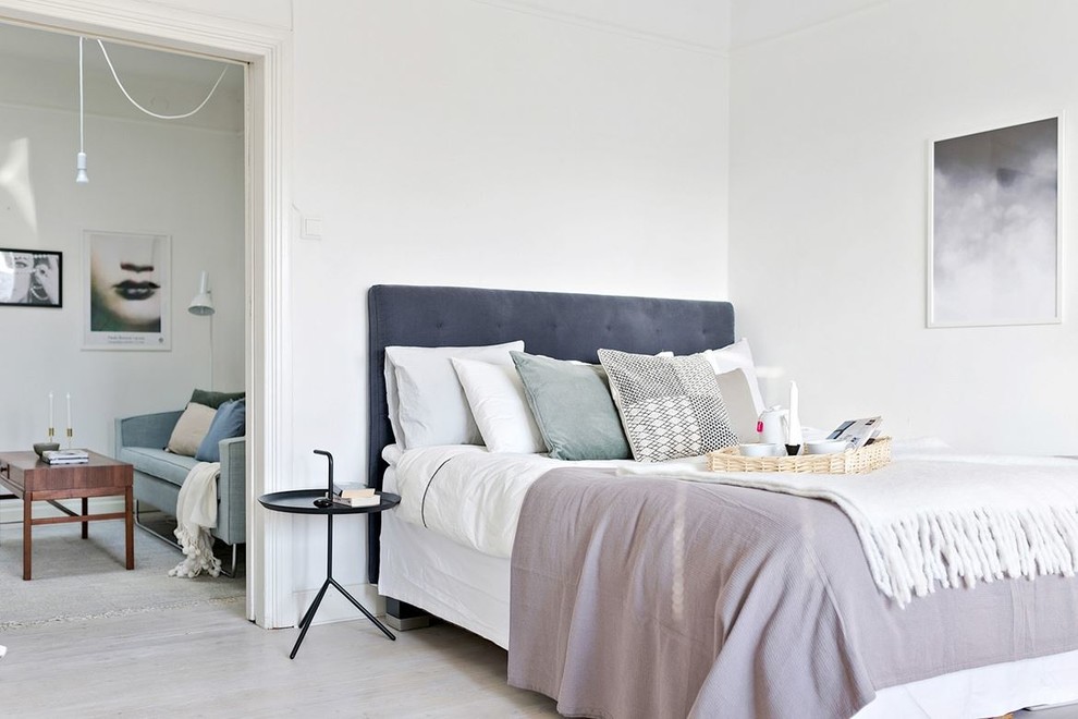 На фото: большая хозяйская спальня в скандинавском стиле с белыми стенами и светлым паркетным полом с