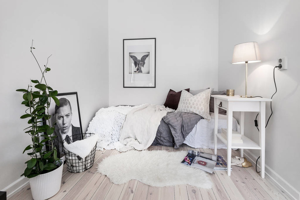 Modelo de dormitorio principal nórdico pequeño con paredes blancas y suelo de madera clara