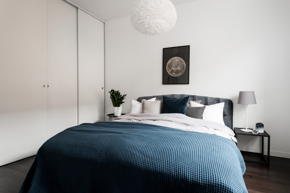 Пример оригинального дизайна: гостевая спальня (комната для гостей) в скандинавском стиле с белыми стенами, темным паркетным полом и коричневым полом