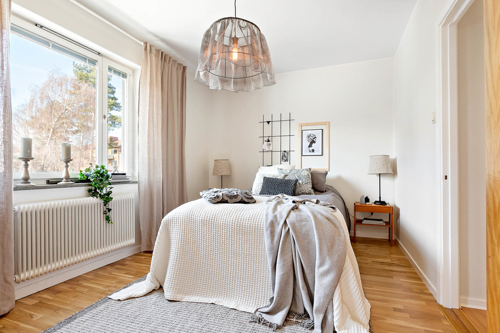 Photo of a medium sized scandinavian guest bedroom in Stockholm with white walls and light hardwood flooring.
