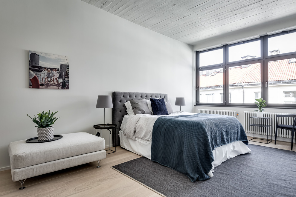 Photo of a large scandinavian master bedroom in Stockholm with white walls, light hardwood flooring and beige floors.