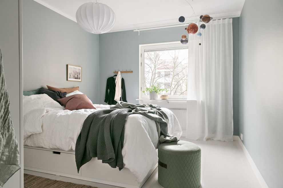 Diseño de dormitorio nórdico sin chimenea con paredes azules, suelo de madera pintada y suelo blanco