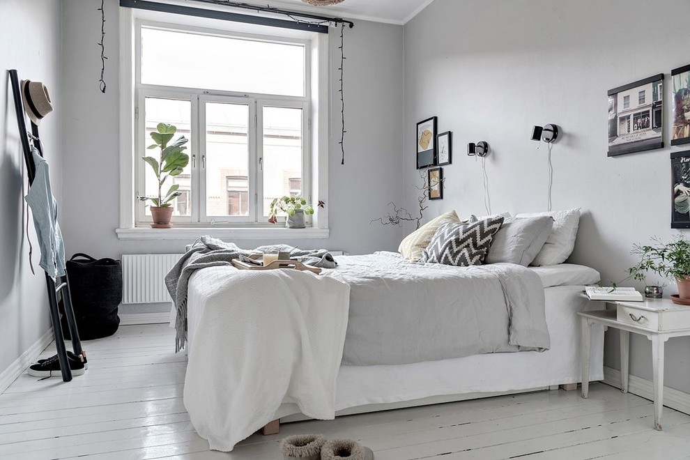 Inredning av ett minimalistiskt sovrum, med grå väggar, målat trägolv och vitt golv