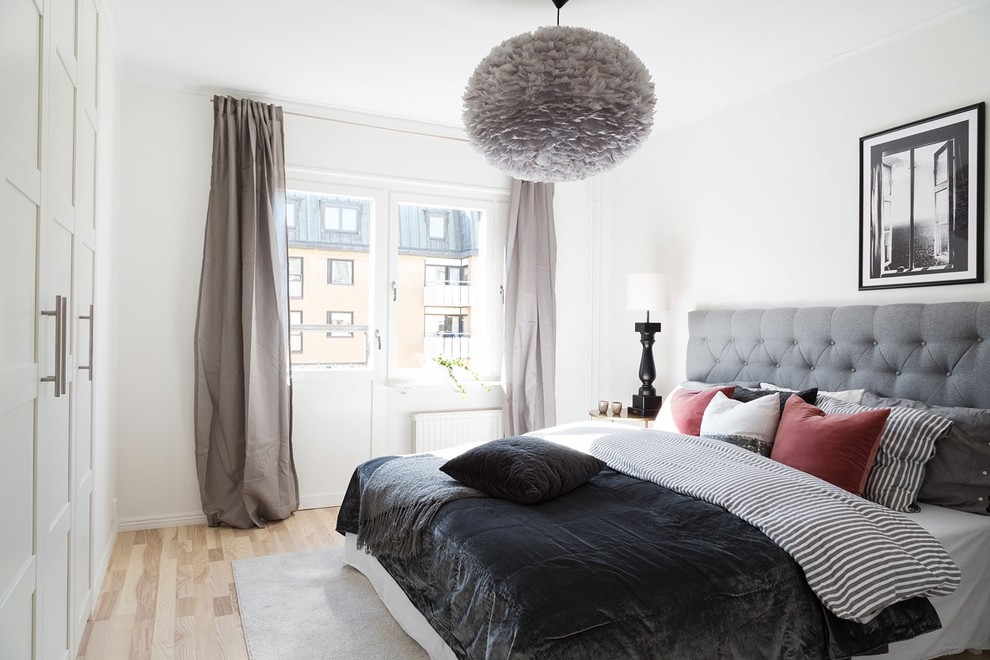 Inspiration for a scandi guest bedroom in Gothenburg with white walls, light hardwood flooring and beige floors.
