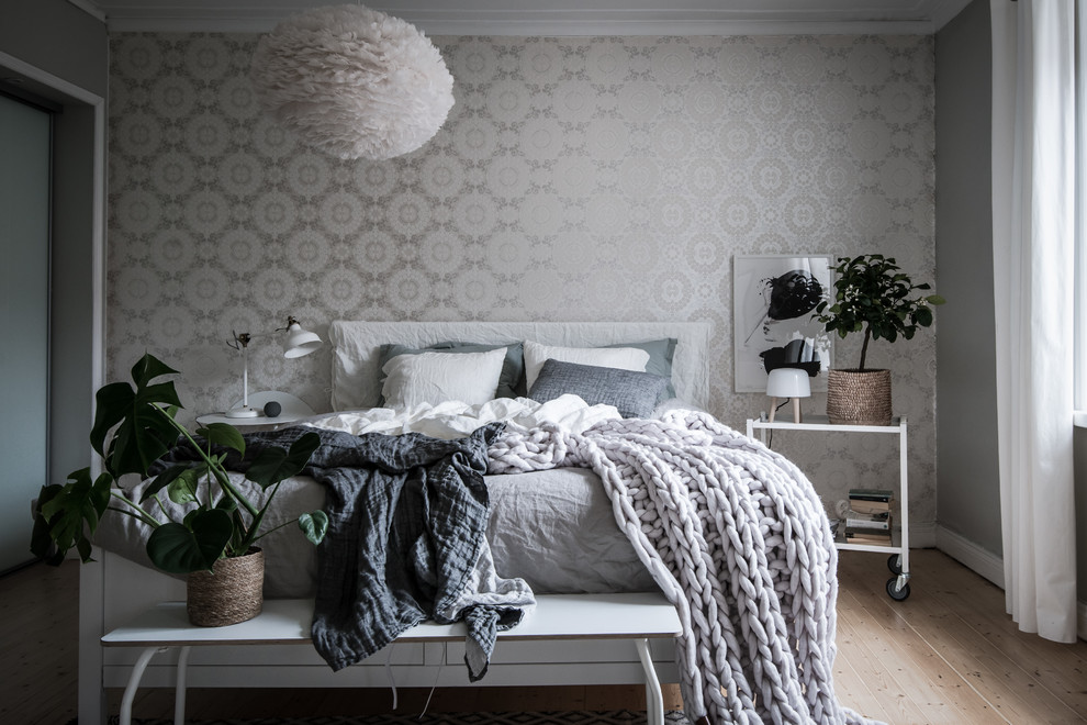 Foto de dormitorio escandinavo con paredes grises y suelo de madera clara