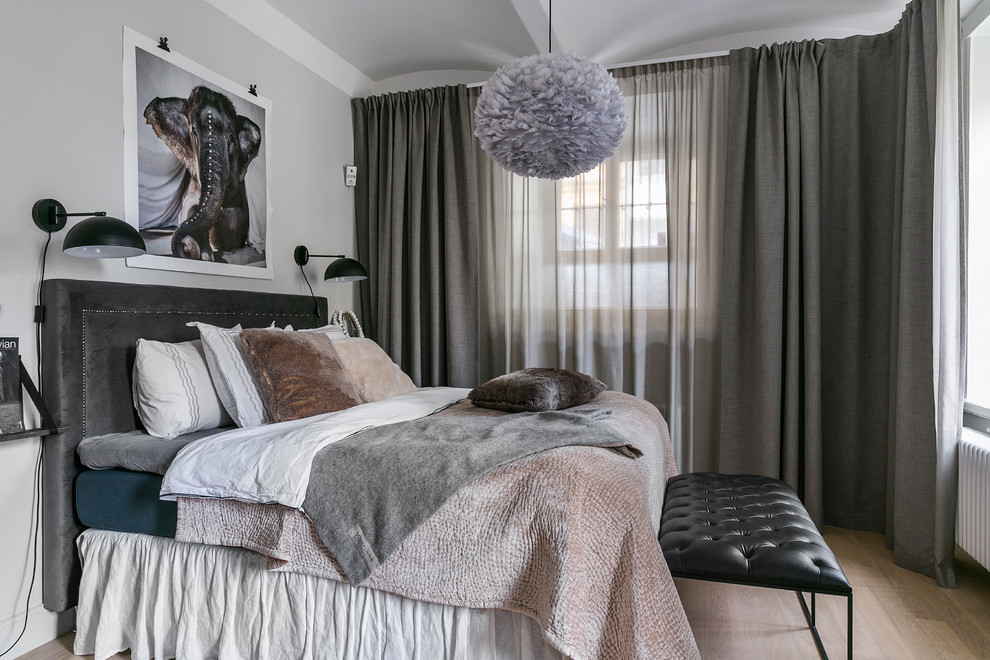 Bild på ett minimalistiskt sovrum, med grå väggar, mellanmörkt trägolv och brunt golv