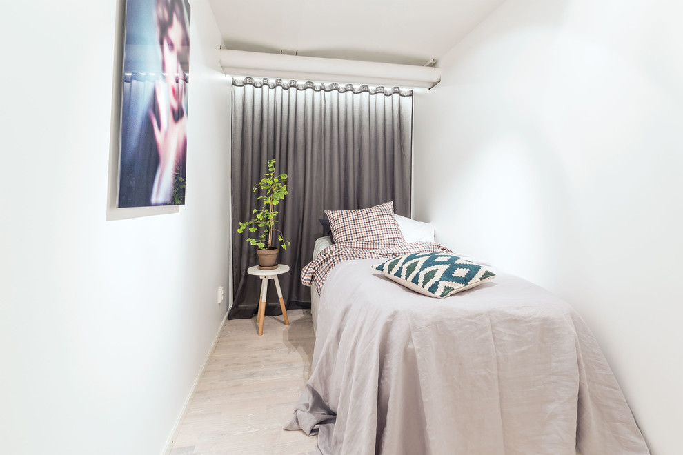Photo of a small scandinavian bedroom in Stockholm with white walls, light hardwood flooring and no fireplace.