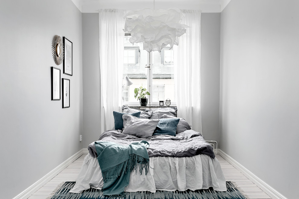 Cette image montre une chambre parentale nordique de taille moyenne avec un mur gris et parquet clair.