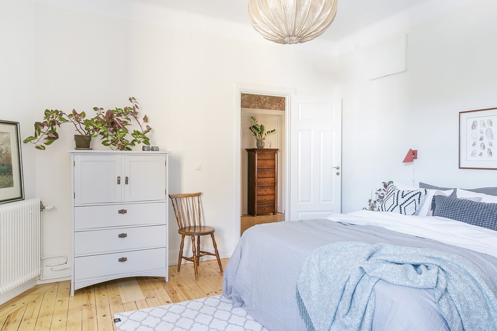 Imagen de dormitorio principal nórdico de tamaño medio con paredes blancas, suelo de madera clara y suelo beige