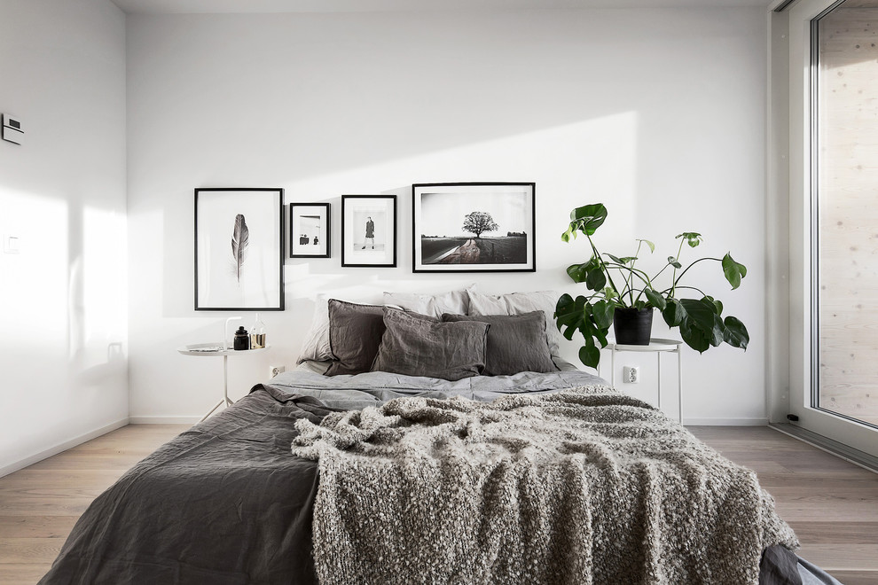 ストックホルムにある中くらいな北欧スタイルのおしゃれな主寝室 (白い壁、淡色無垢フローリング) のインテリア