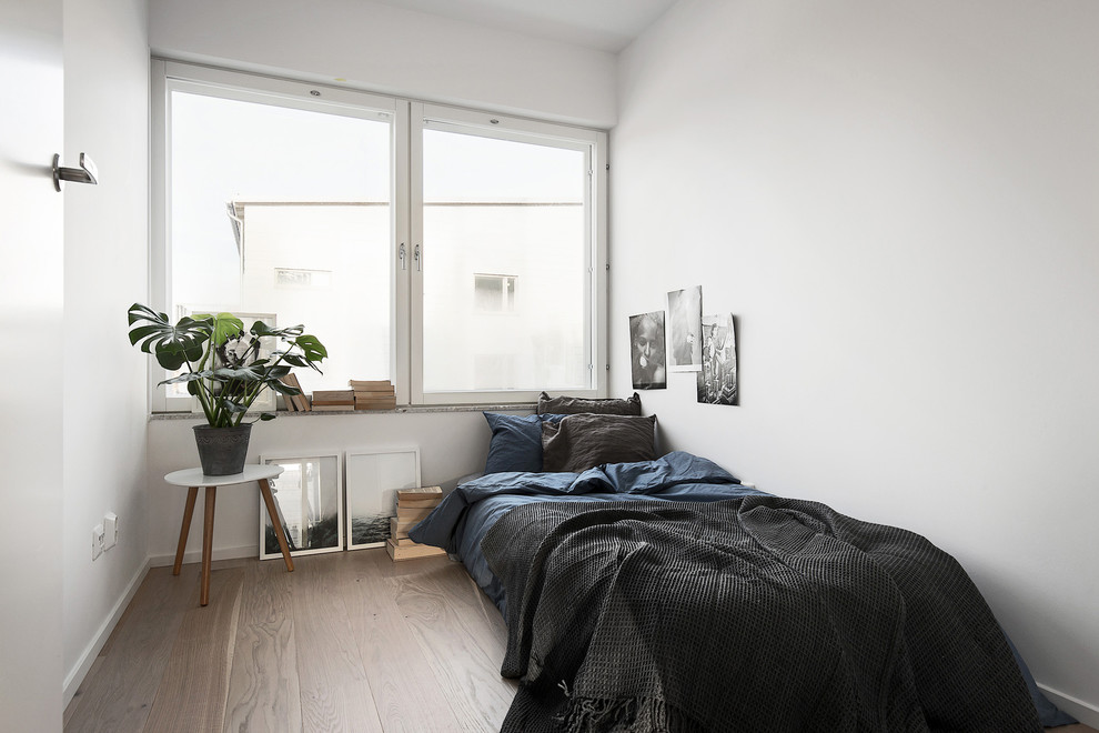 Immagine di una camera da letto scandinava di medie dimensioni con pareti bianche e pavimento in legno massello medio