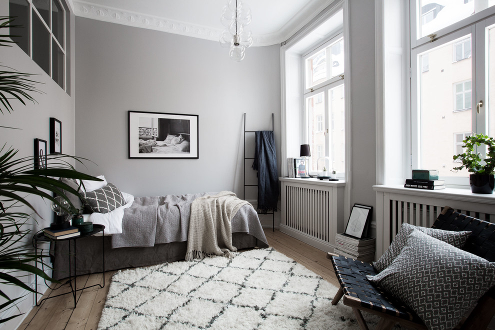 Medium sized scandinavian master bedroom in Stockholm with grey walls, light hardwood flooring and no fireplace.
